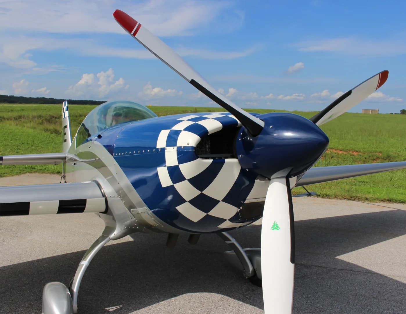 A front view of the N51E Extra EA-300/L aircraft, showing its blue and white checkered nose and propeller.