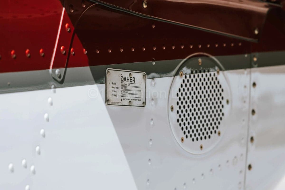 A close-up view of the DAHER data plate and a vent on the aircraft's fuselage.