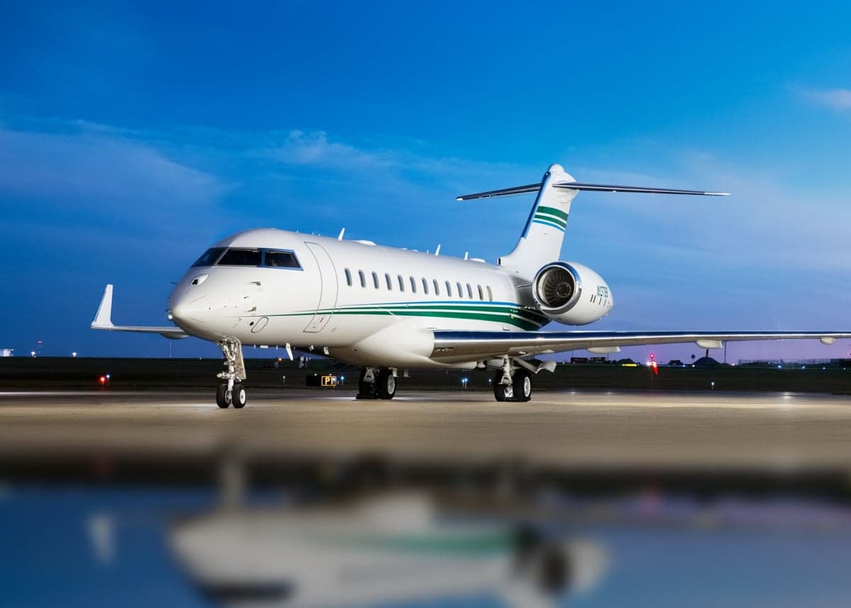 A white Bombardier Challenger aircraft is parked on the tarmac at dusk.