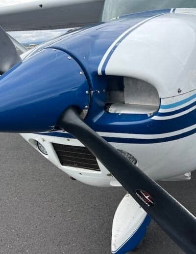 Close-up of the aircraft's propeller and nose, featuring a blue and white paint scheme.