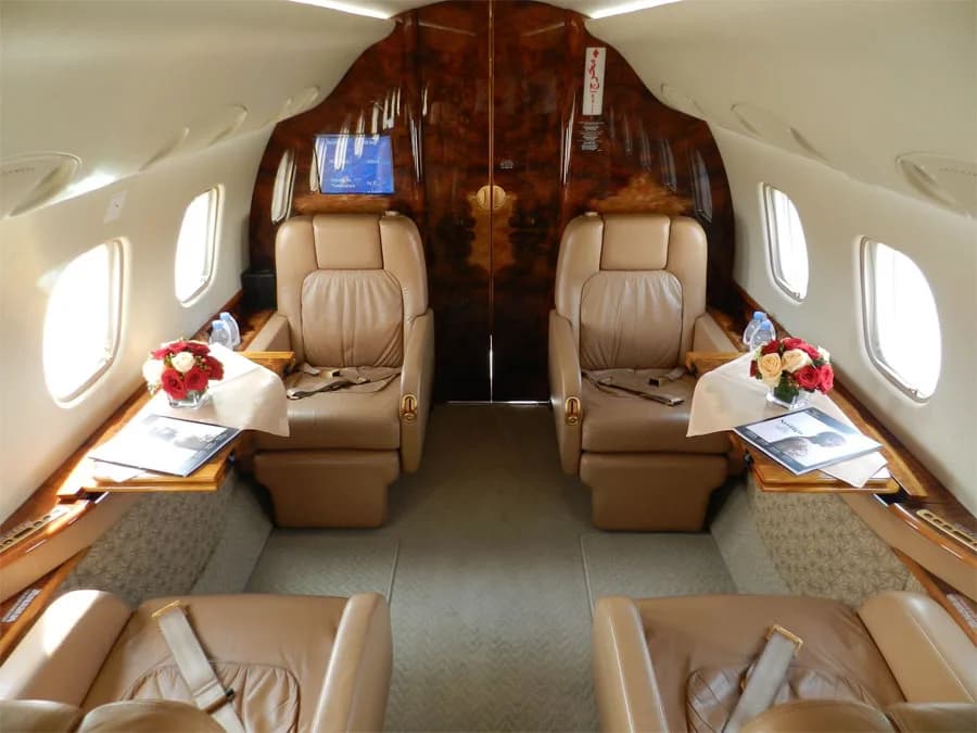 The luxurious interior of an aircraft cabin features two large leather seats and polished wood accents.