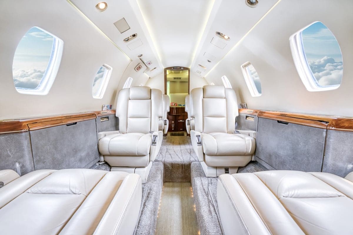 The interior of the aircraft features white leather seats and wood trim.