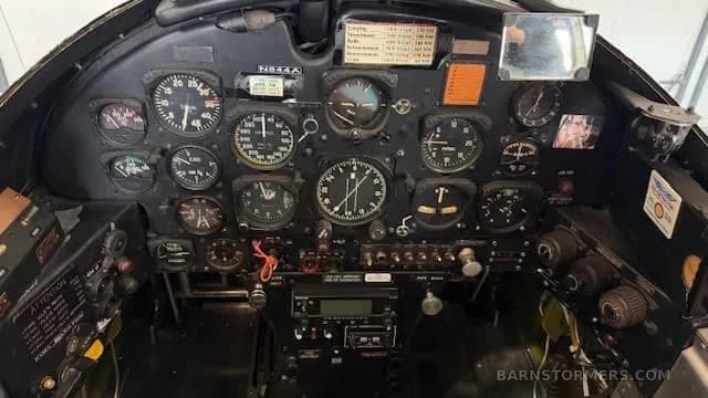 The full instrument panel of an aircraft cockpit, featuring numerous analog gauges and a modern radio stack below.