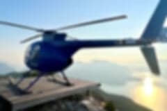 A blue helicopter parked on a snowy mountain.