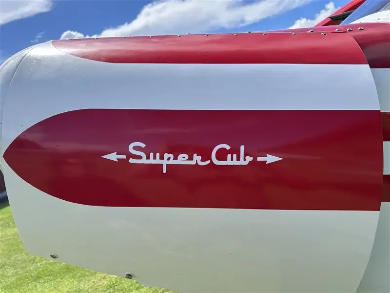 A close-up of the aircraft's red and white fuselage with "Super Cub" written in white script.