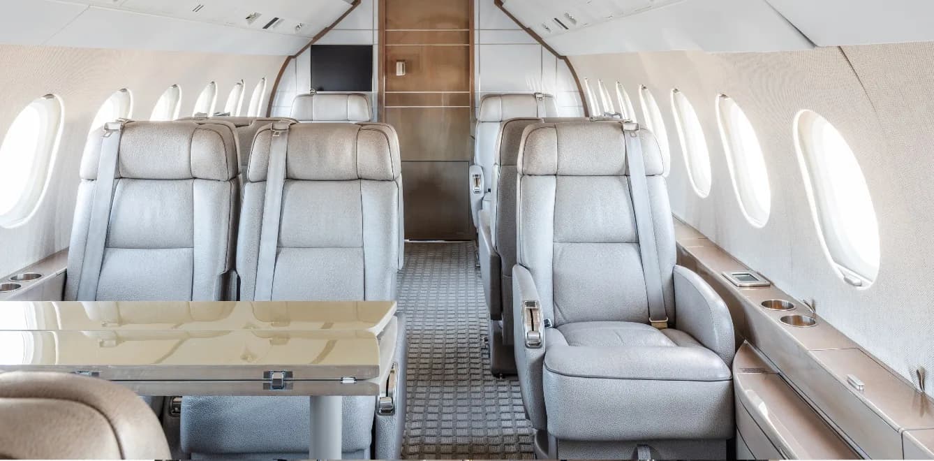 View of the aircraft's interior with light gray leather seats and a table.