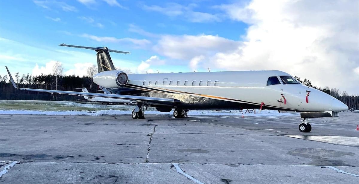 Side view of a white and black Embraer Legacy 650 on the tarmac.