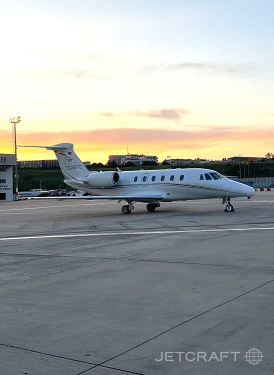 A white Cessna Citation business jet with tail number TC-BTO parked on an airport tarmac at sunset.