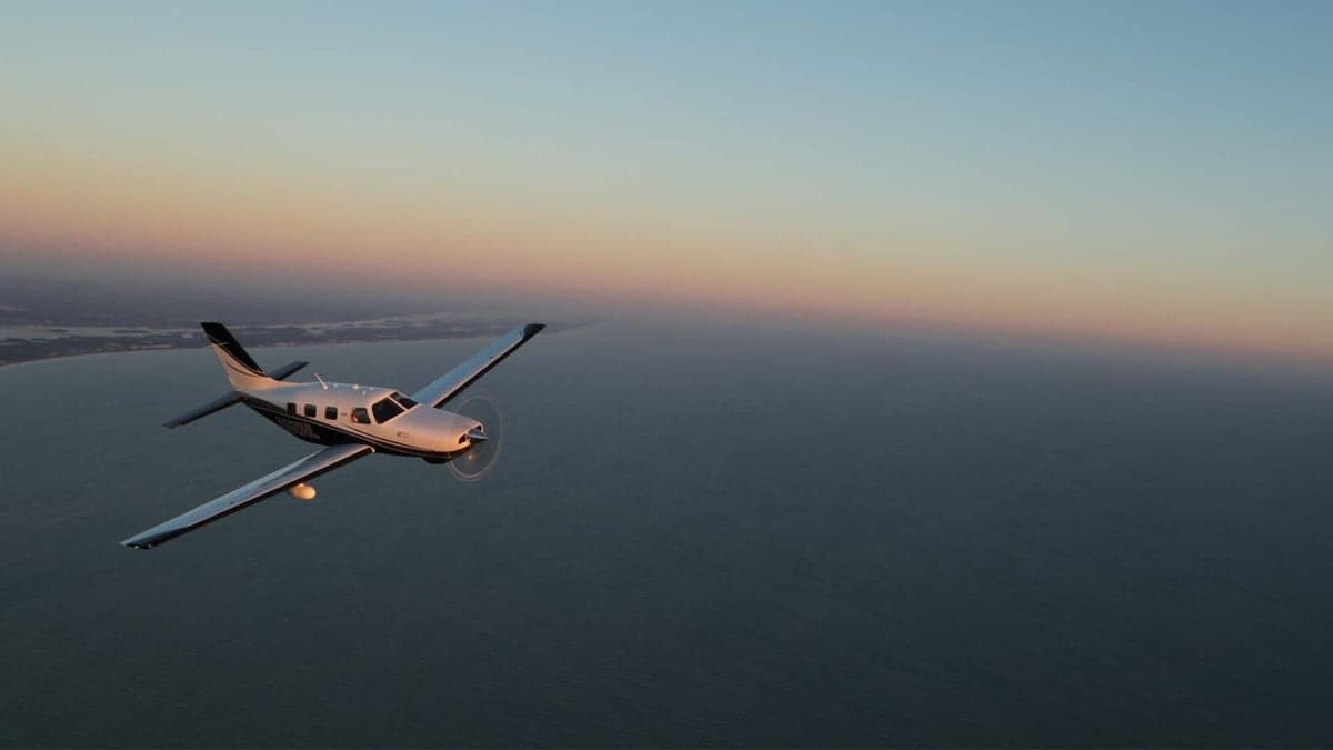 A Piper M600 in flight over the ocean at sunset.