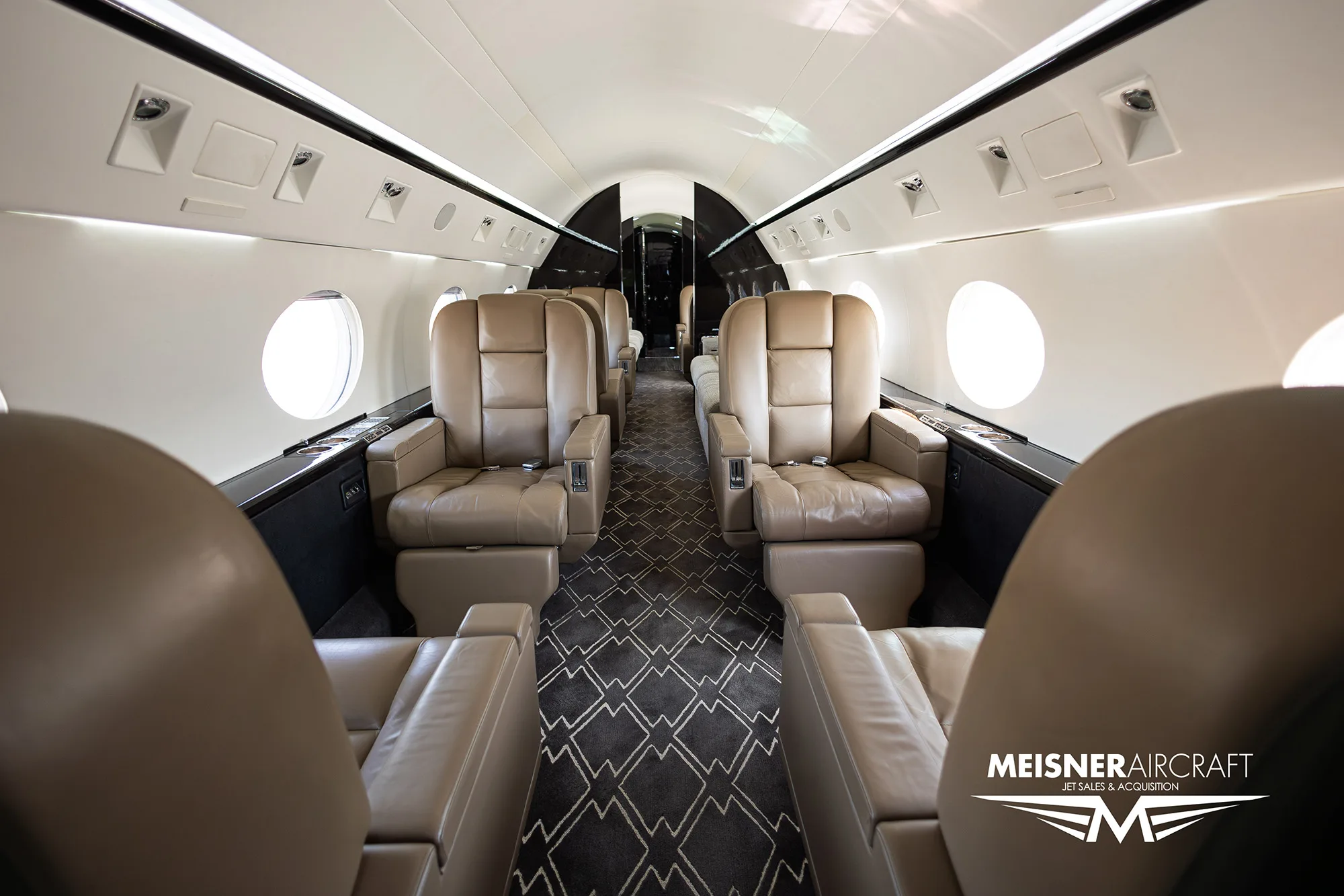 Interior of the aircraft cabin with leather seats and patterned carpet.