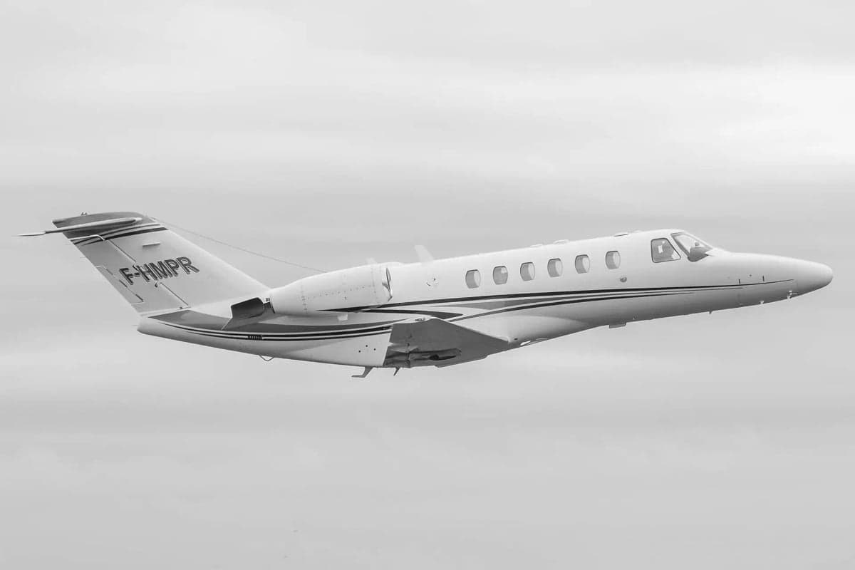 A Cessna Citation CJ2 aircraft with registration F-HMPR in flight, shown in black and white.