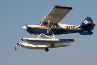 Blue and white seaplane flying in the sky.