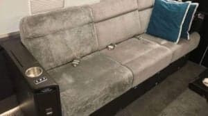 A gray fabric divan with seatbelts is shown inside the aircraft cabin.