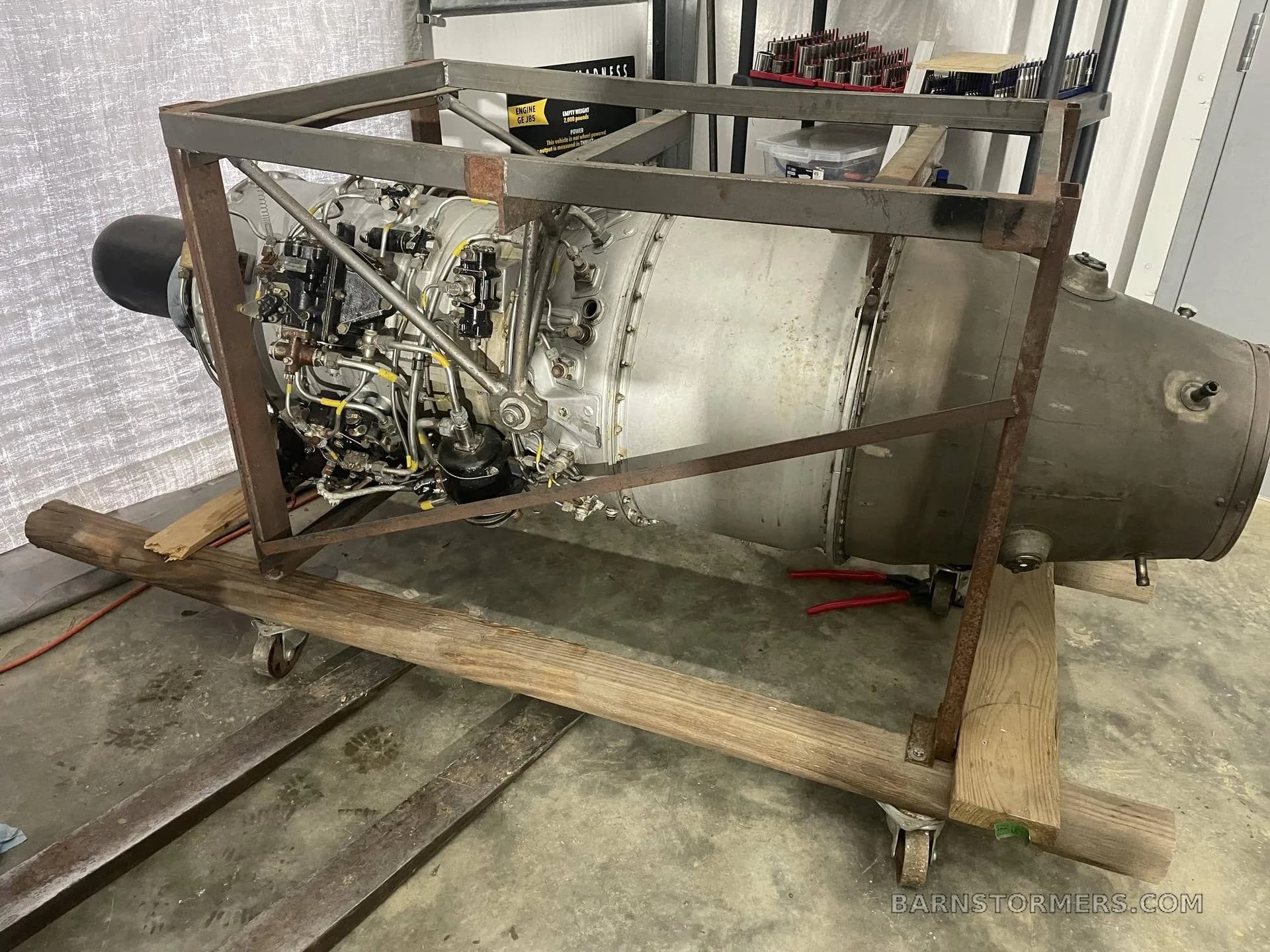A large aircraft jet engine on a wooden and metal stand in a workshop.