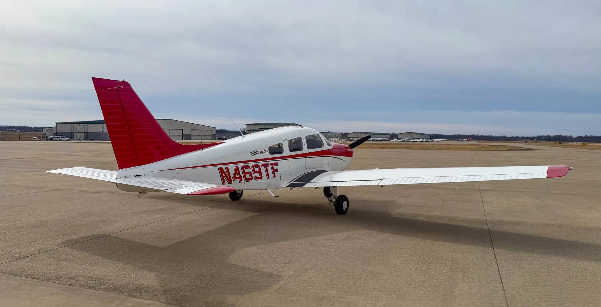 A three-quarter front view of a white and red Piper Archer TX aircraft, N469TF, on an airfield.