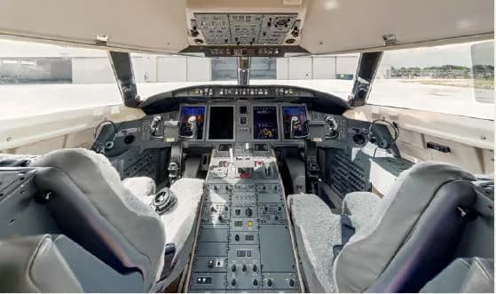 The cockpit of a business jet, showing the instrument panel, control yokes, and pilot seats.