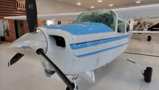Close up of the front of a Cessna Centurion aircraft with a blue and white paint scheme.