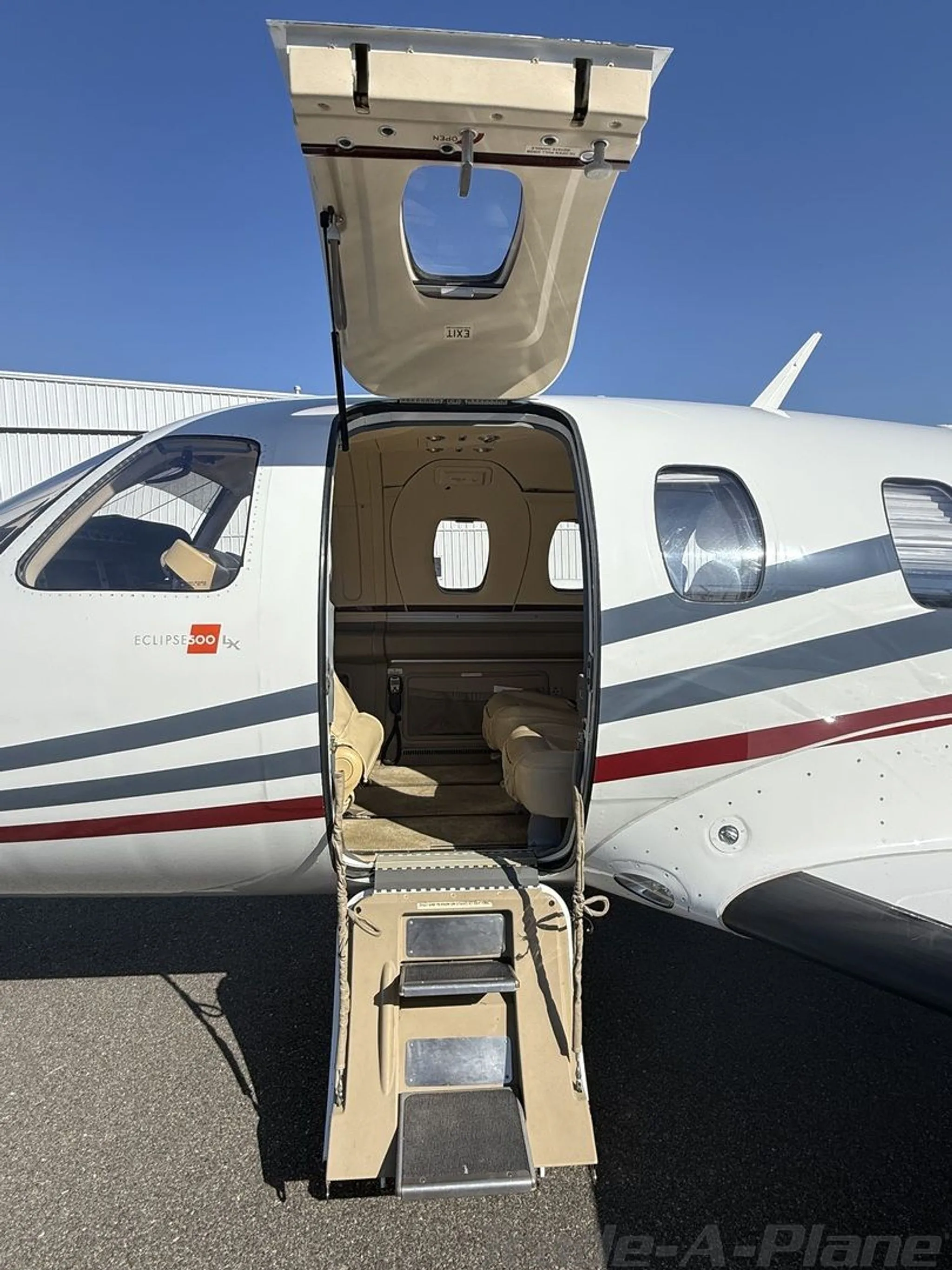 The open main cabin door and integrated stairs of a white Eclipse 500 LX jet, revealing the beige interior.