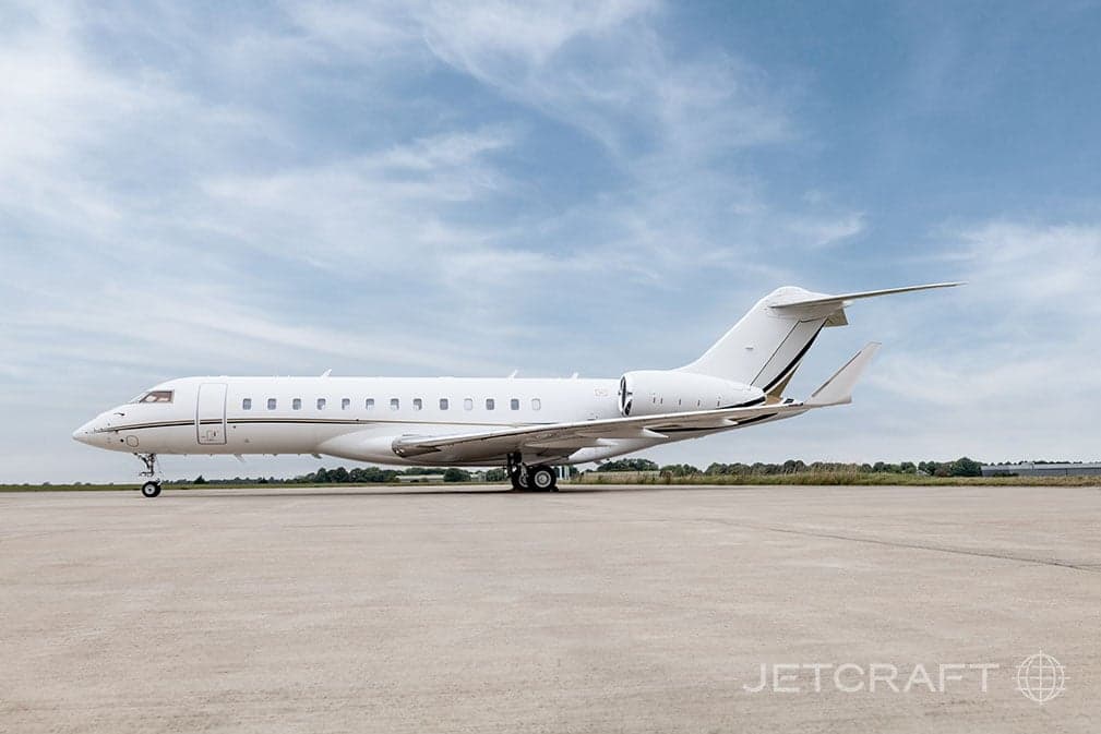 Side view of a white and gold Bombardier Global Express on the tarmac.
