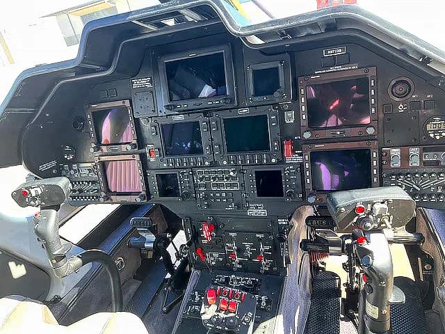 View of the helicopter cockpit with multiple display screens and controls.