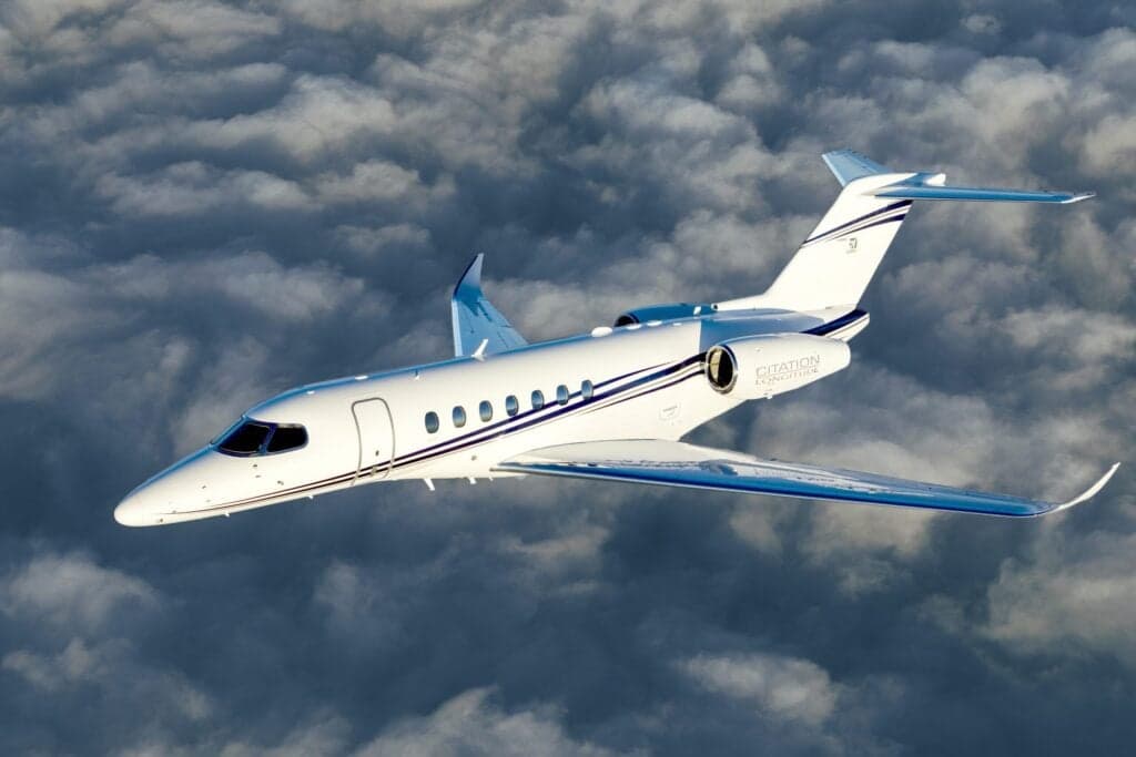A Citation Longitude jet in flight above the clouds.