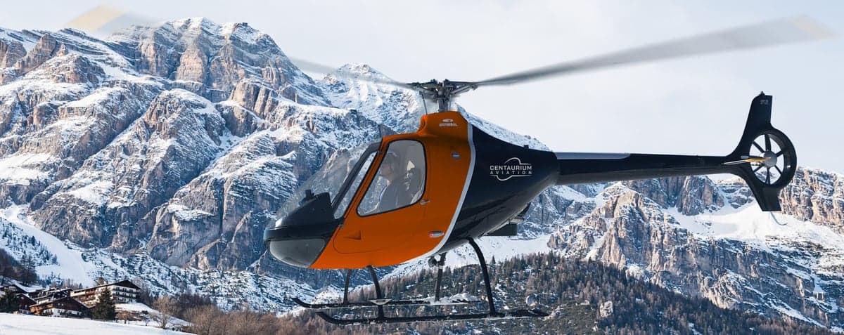 Stock photo of a Centaurium Aviation helicopter in flight over a snowy mountain landscape.