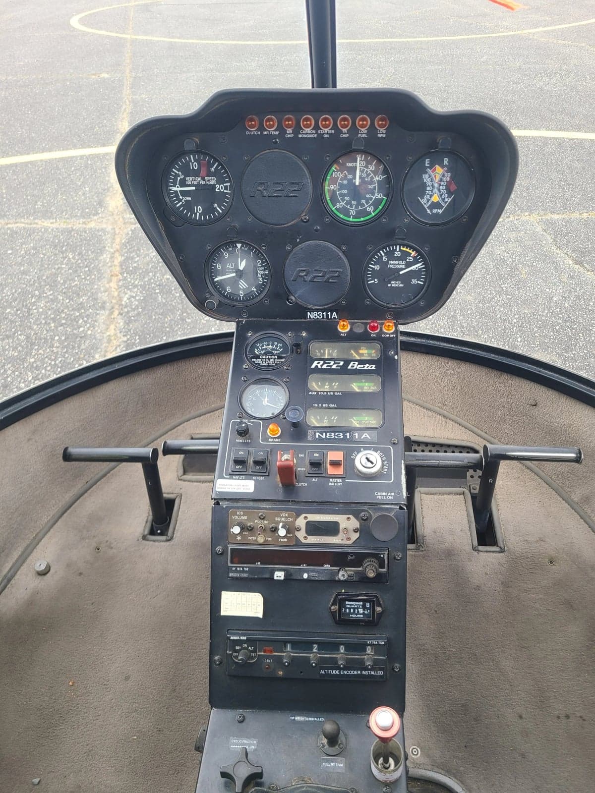 The instrument panel and center console of a Robinson R22 Beta helicopter, showing gauges and controls.
