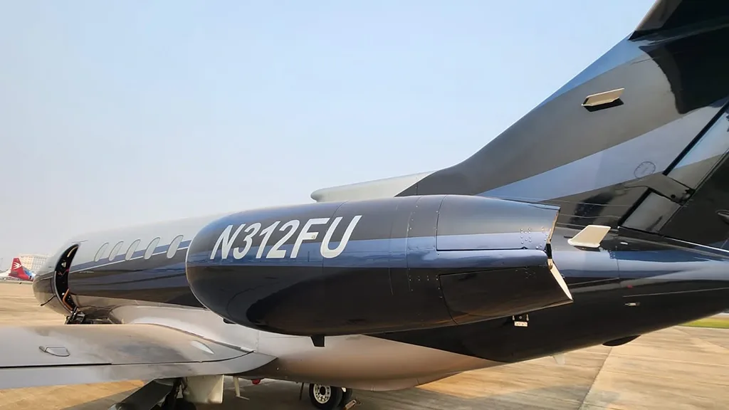 A close-up view of the tail and engine of a dark blue and silver business jet with registration N312FU.