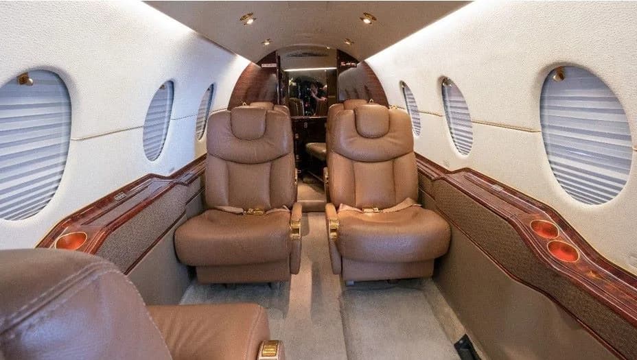 Aircraft interior with four leather seats and wood trim.