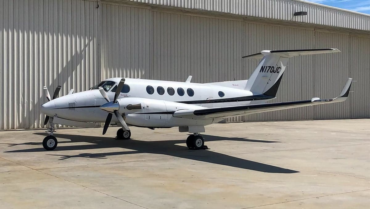 A Beechcraft King Air 200, tail number N170JC, parked in front of a hangar.