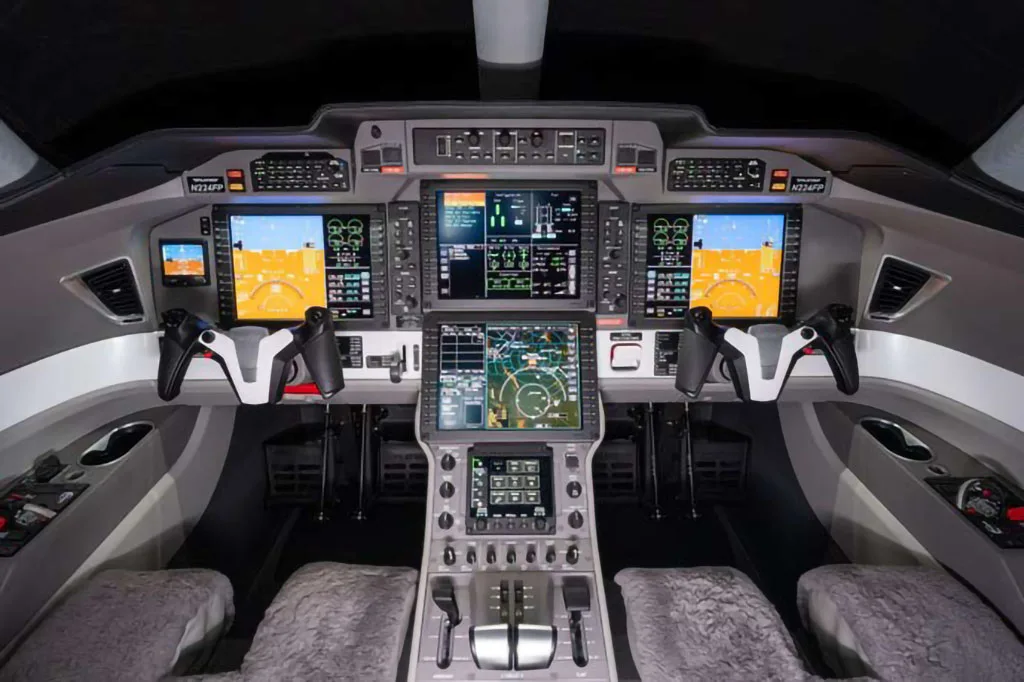 The modern cockpit of a Pilatus PC-24 jet features multiple large digital displays and flight controls.