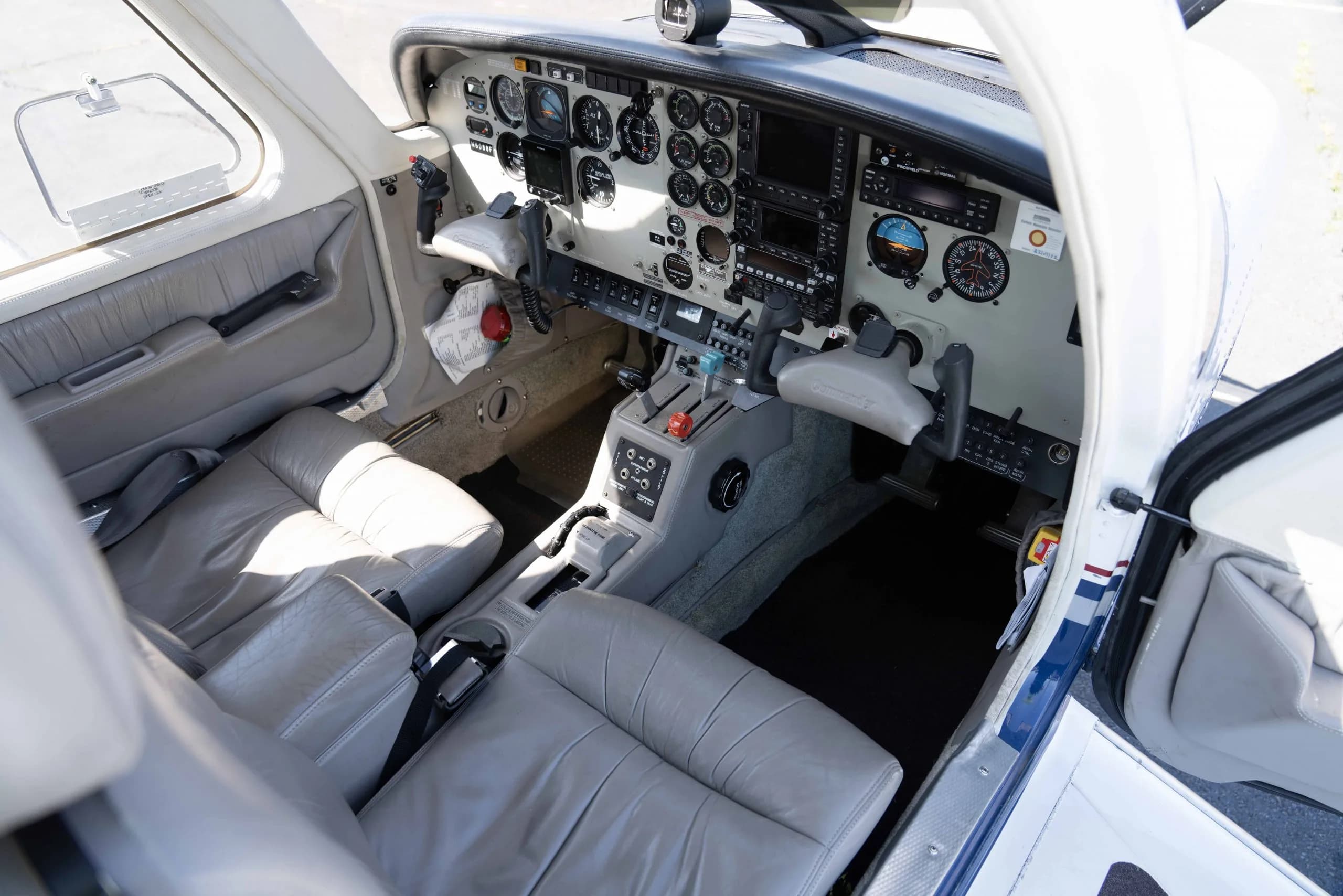 The cockpit of the aircraft with light grey seats and a detailed instrument panel.