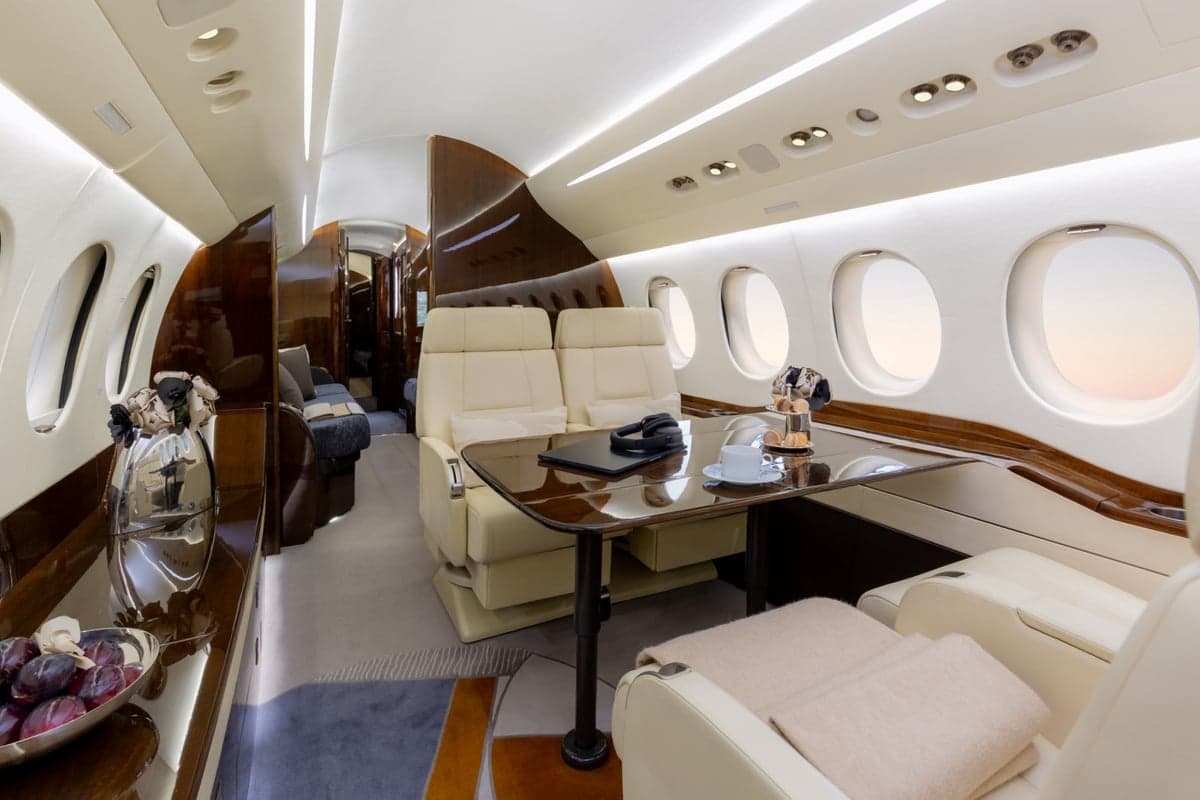 View of the aircraft interior with cream-colored seats and a table set with snacks.