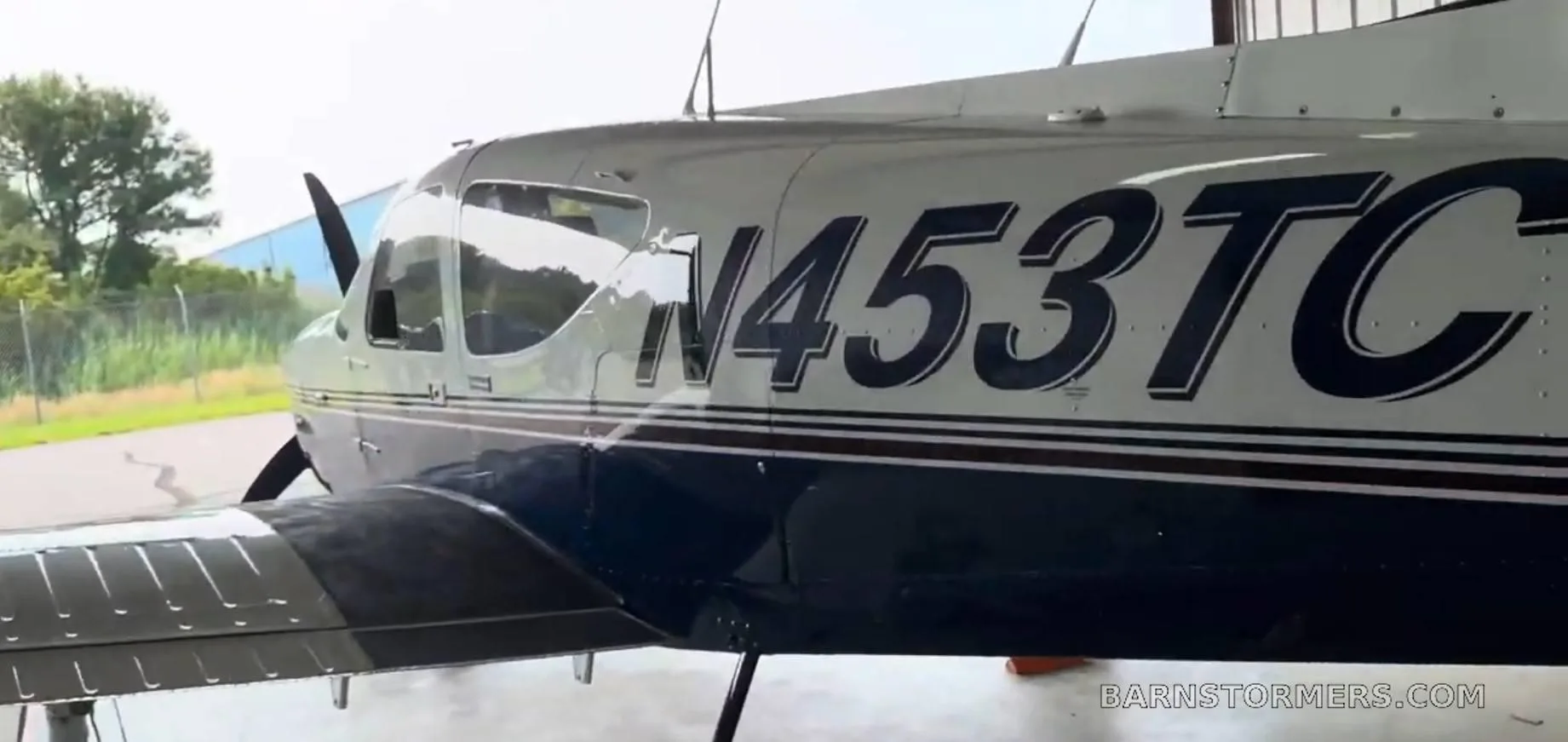 A close-up side view of the white and blue single-engine aircraft N453TC inside a hangar.