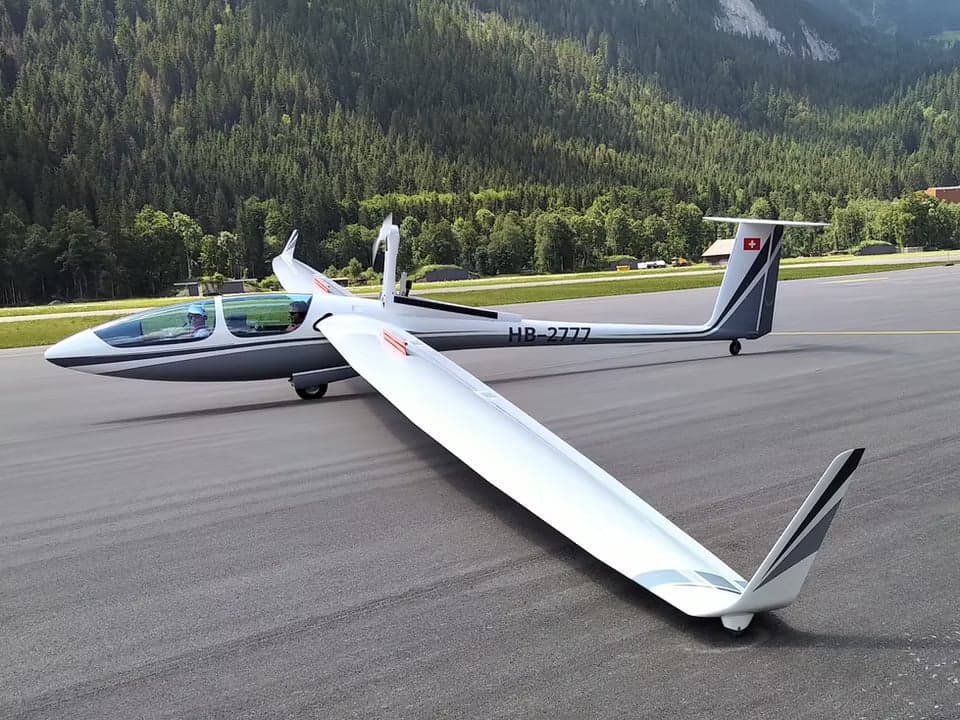 A glider with open cockpit on the ground.