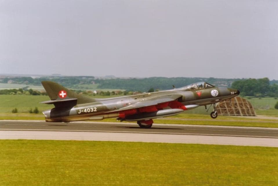 Line of Hawker Hunter aircraft with Swiss Air Force markings on the tarmac.
