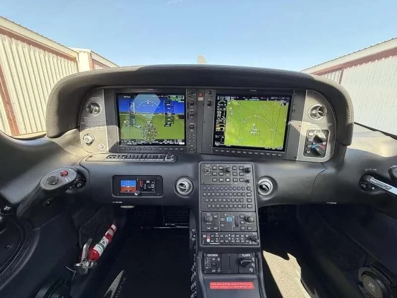 The cockpit instrument panel of the aircraft, featuring two large display screens and numerous controls.