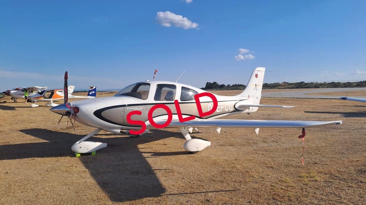 A Cirrus aircraft with registration D-EFCG is parked on a grassy airfield with the word SOLD overlaid.