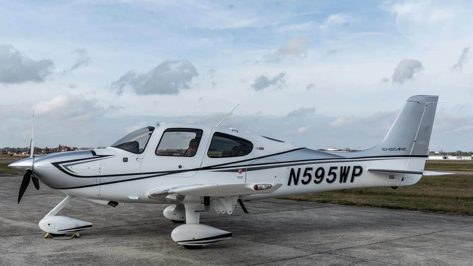 A white Cirrus SR22 aircraft with silver and black accents, registration N595WP, parked on an airfield.