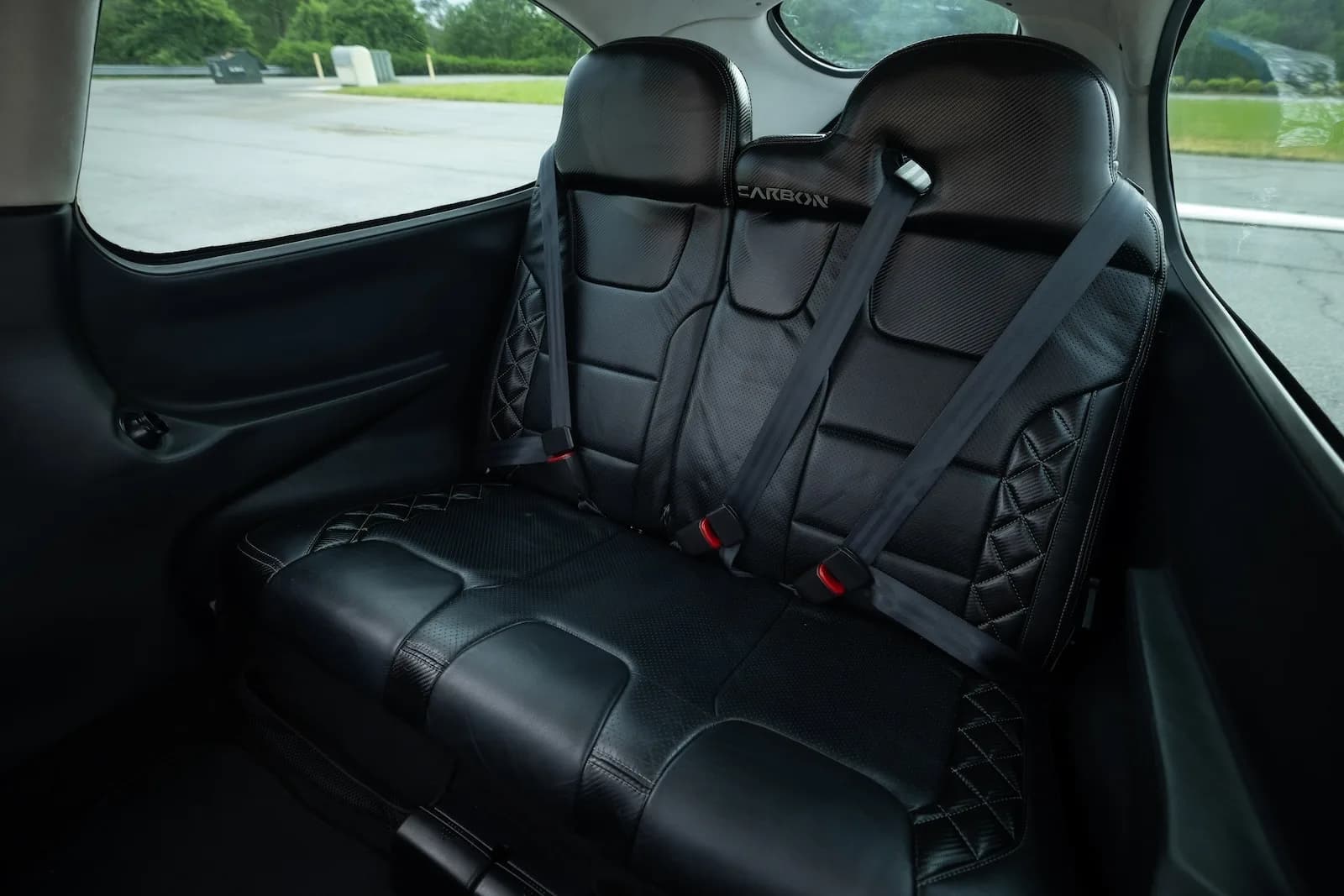 A close-up view of the black leather rear seats with diamond stitching in the aircraft cabin.