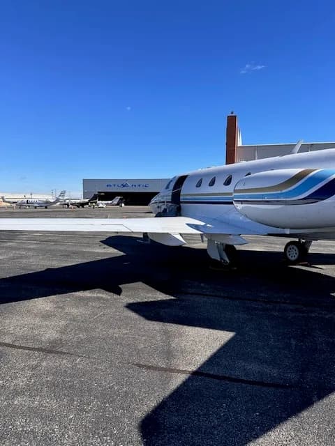 The N700JC business jet parked on the tarmac next to an "Atlantic" hangar, with its main cabin door open.