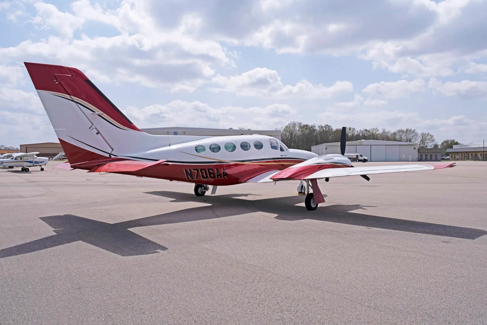 A three-quarter rear view of a white and red Cessna 421C Golden Eagle with registration N706AA on an airfield.