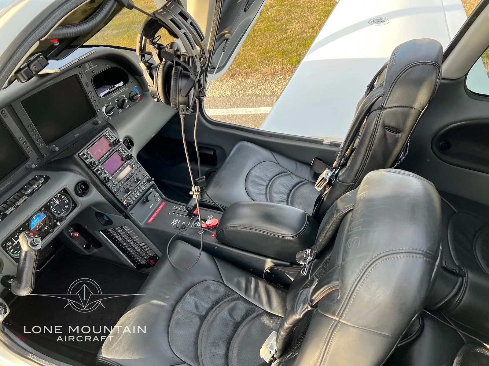 The cockpit and front black leather seats of a Cirrus SR22 aircraft, showing the instrument panel and controls.