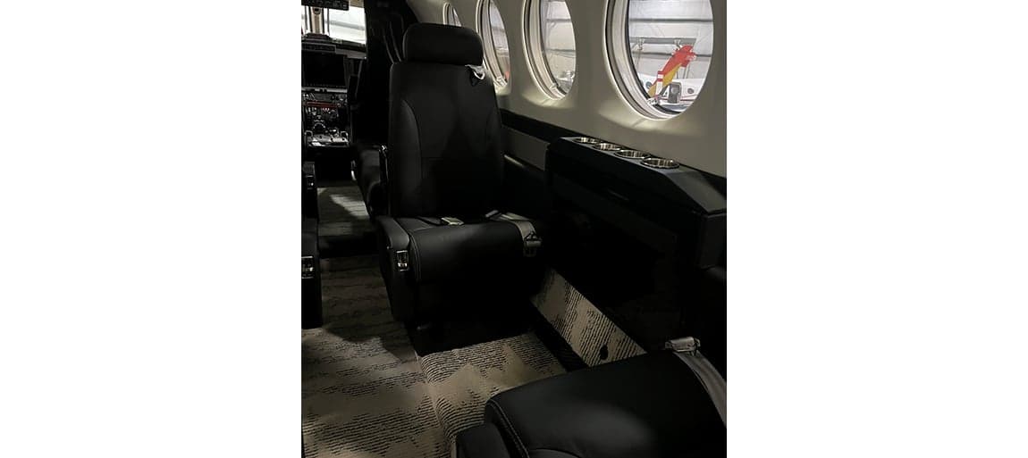 View of the aircraft interior showing the black leather seats and carpeted floor.