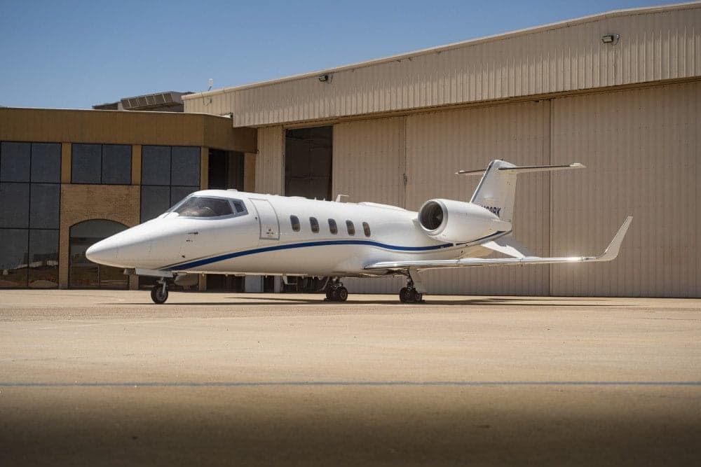 A Learjet 31A aircraft parked on the tarmac in front of a hangar.