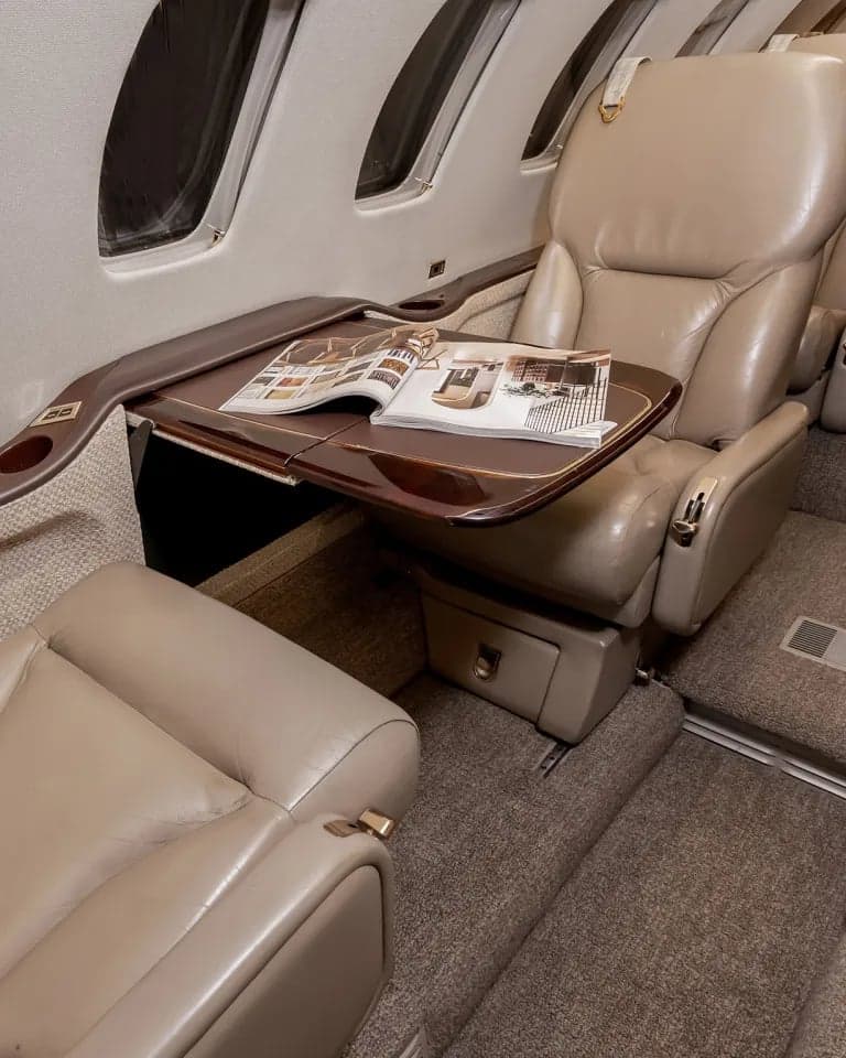 View of the aircraft interior showing a seat with a table and magazine.