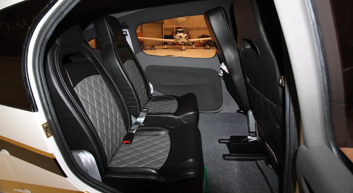 The interior of the aircraft features black leather seats with a diamond-stitched pattern.