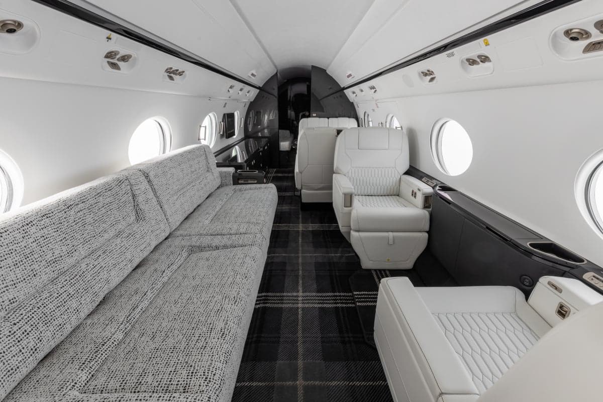 Interior view of the aircraft cabin with a grey sofa and white leather seats.