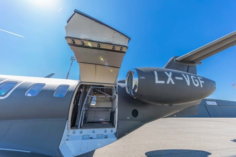 A Bombardier Challenger 350 aircraft with registration LX-VGF is parked on the tarmac at an airport.