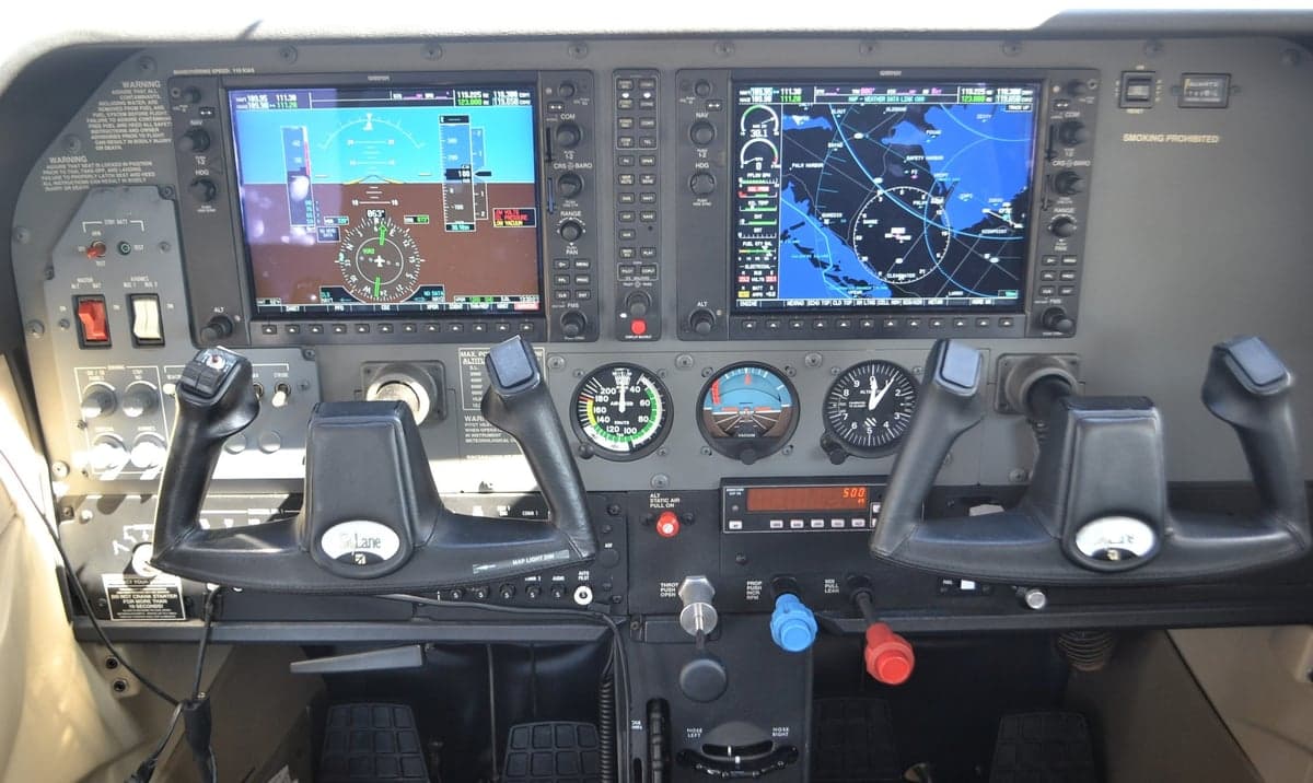 The instrument panel of the aircraft with dual screens and flight controls showing navigation information.